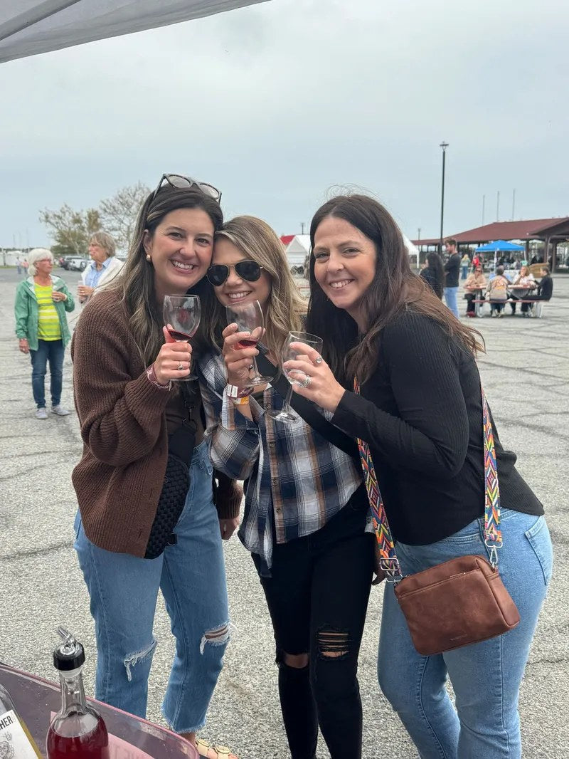 Three women toasting with Tipsy Teacher wine at a festival